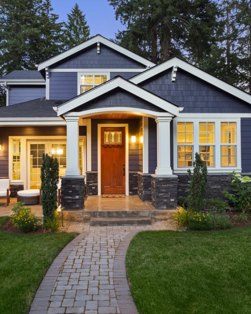 Craftsman-style home with vinyl windows and lit interior showcasing residential window installation