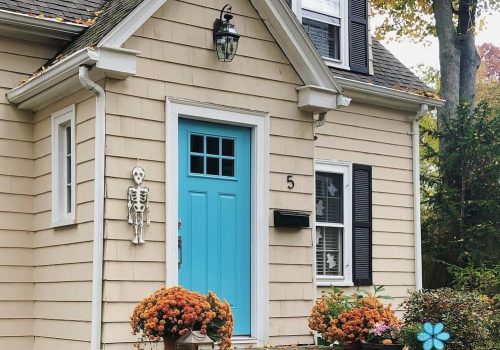 Small home exterior with vinyl window and blue front door showcasing residential window installation