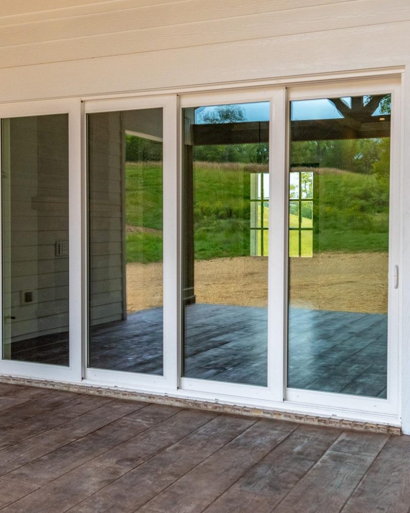 Large white vinyl sliding glass doors installed on patio with outdoor view