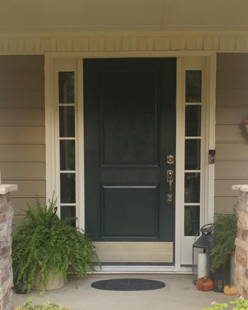 Black front entry door with narrow glass sidelights on residential home exterior